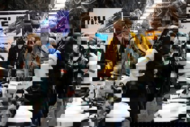 Several young people and a teacher at a scientific display study and interact with the equipment, they are at The Big Bang Fair