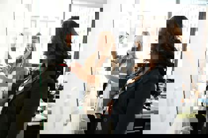 Two people in an office environment work at a whiteboard, smiling