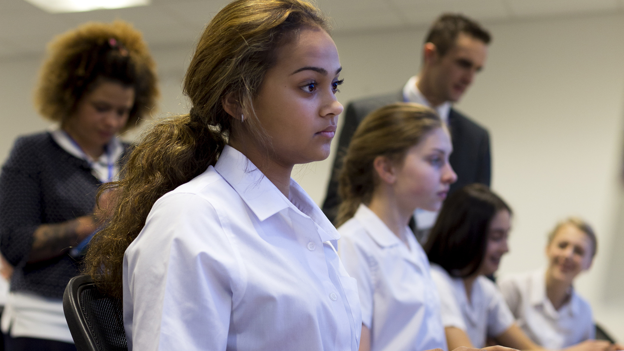 A group of secondary school students and their teacher in a school computer room working  
