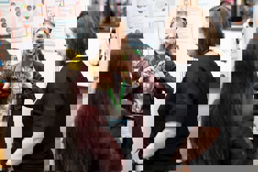 A young person at their Big Bang Competition stand at The Big Bang Fair shows their Competition entry to two visitors