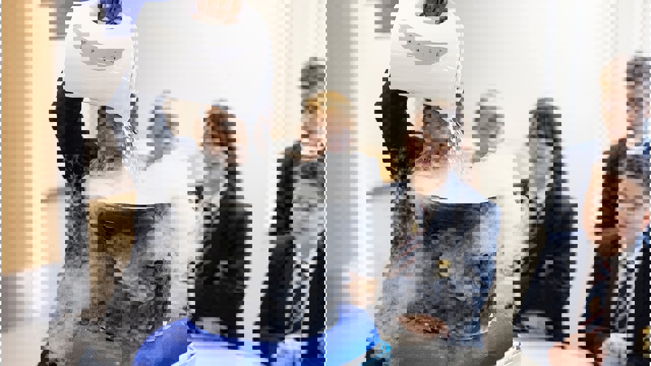 Young people in school science lab working on an experiment as others look on 