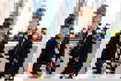 Two young people in a school science lab work on an experiment. They smile. 