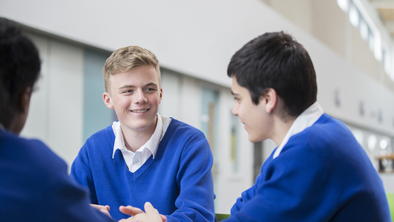A group of secondary school boys in uniform are chatting