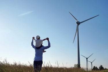 A man and young child by wind turbines