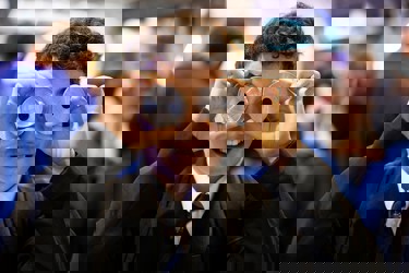 A young person at The Big Bang Fair holds two metal cylindrical pieces in front of their eyes as they smile.