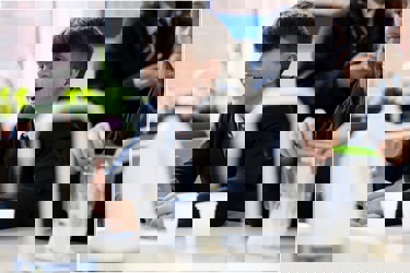 A student in a school science lab smiles as others at his bench work with equipment such as beakers, liquids and chemicals.