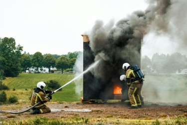 Two fire engineers testing equipment putting out a test fire