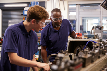 young male student working on equipment with his mentor