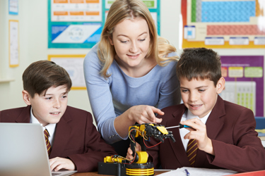 Secondary school student using screwdriver on robot