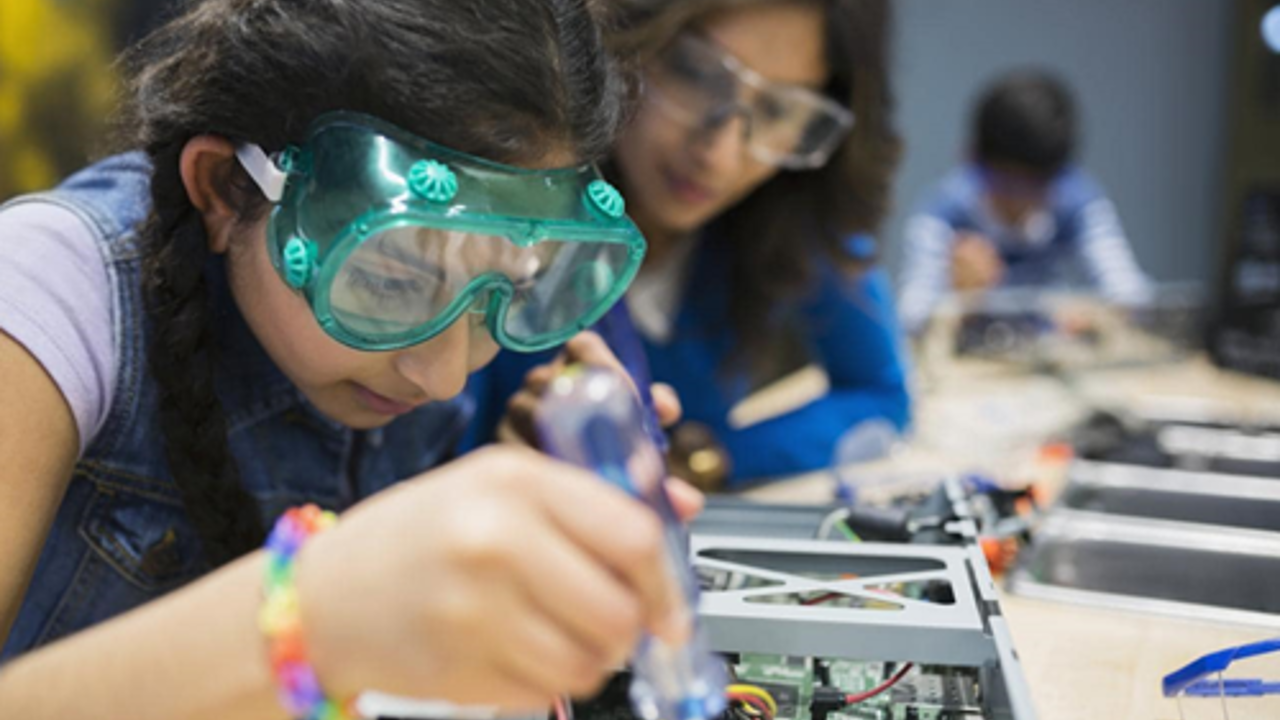 School pupil working with a circuit board with an adult watching on