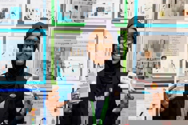 The Big Bang Competition's UK Young Scientist of the Year winner stands and smiles at the camera surrounded by her working boards, photographs and sketches that show how her winning idea developed